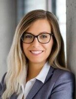 Porträt einer lächelnden Frau mit Brille und blondem Haar